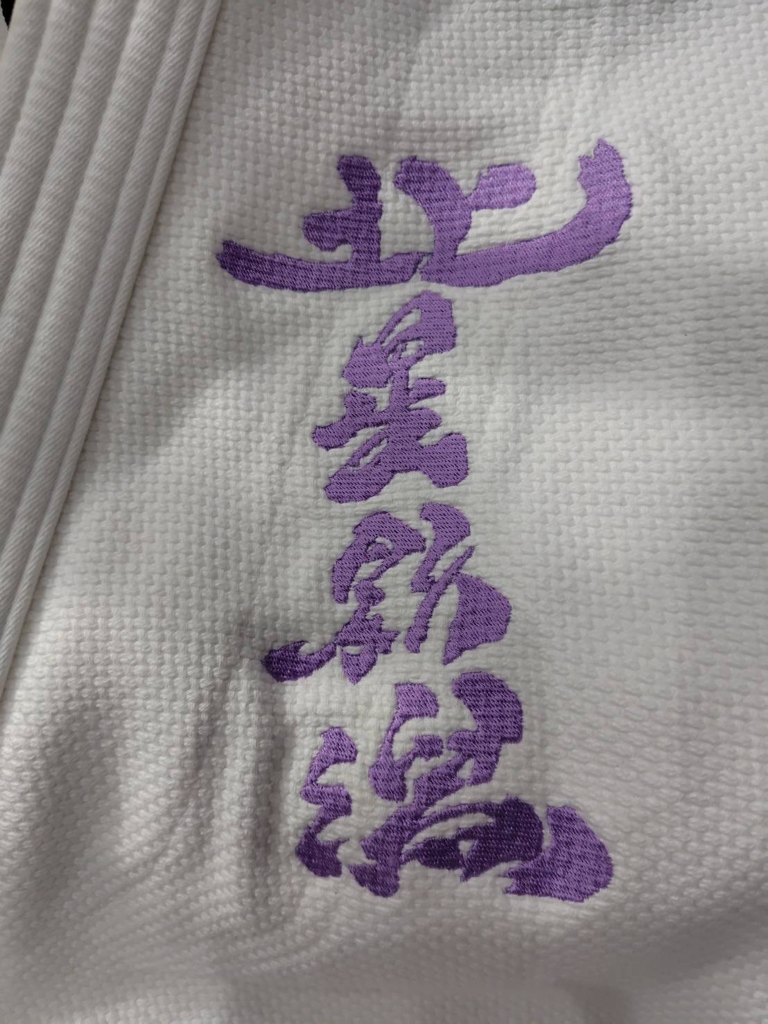柔道着の胸に紫の糸で刺繍された「北星新潟」の文字